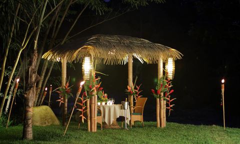 An outdoor dinner
          with thatched roof gazebo, tiki torches, and champagne.