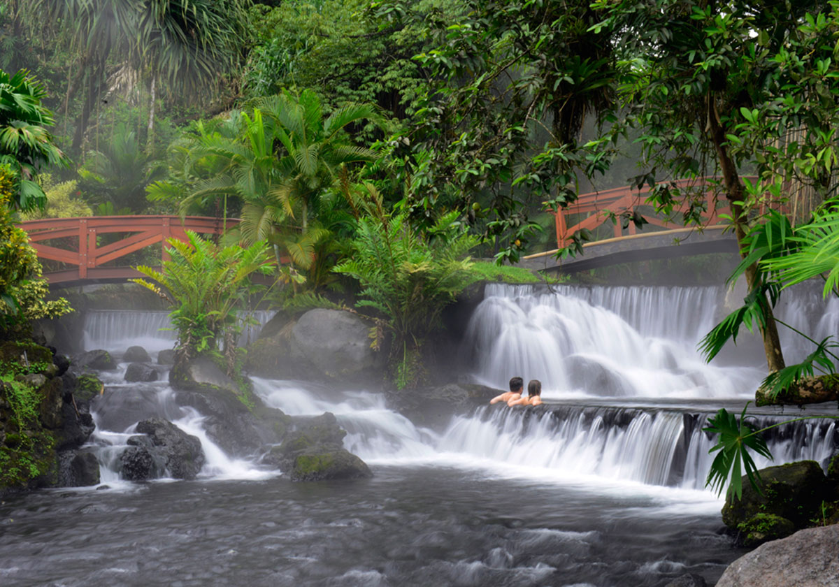 A couple enjoys the lush landscaping and waterfall features of Tabacon Hot Springs.